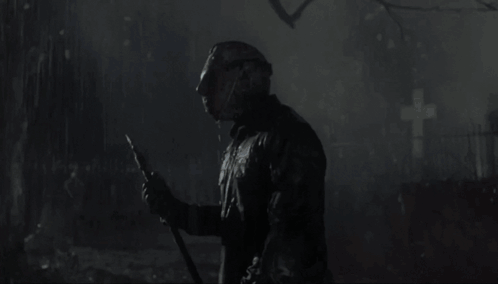 A Man In A Hockey Mask Is Holding A Knife In The Rain GIF