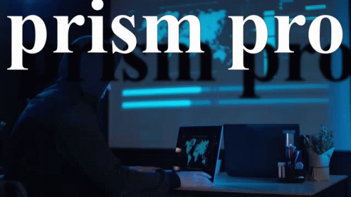 A Man In A Hood Is Using A Laptop In Front Of A Sign That Says Prism Pro GIF