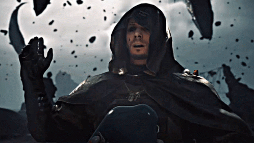 A Man In A Hooded Cape With A Necklace That Says ' A.m. ' On It GIF
