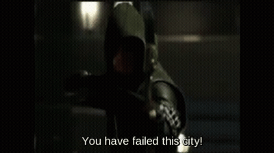 A Man In A Hooded Costume Is Holding A Bow And Arrow And Says `` You Have Failed This City '' . GIF