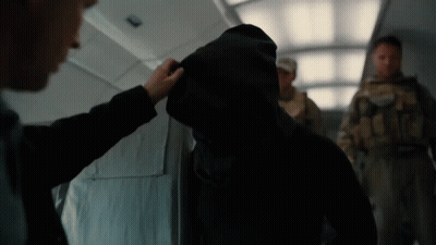 A Man In A Hooded Jacket Is Being Touched By Another Man In A Suit GIF