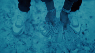 a man in a hooded jacket is holding a fan of money in front of his face