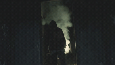 A Man In A Hooded Jacket Is Holding A Light GIF