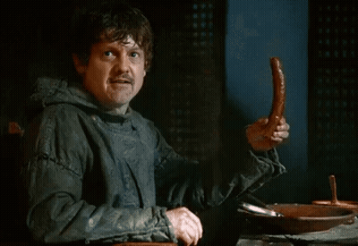 A Man In A Hooded Jacket Is Holding A Sausage In His Hand GIF