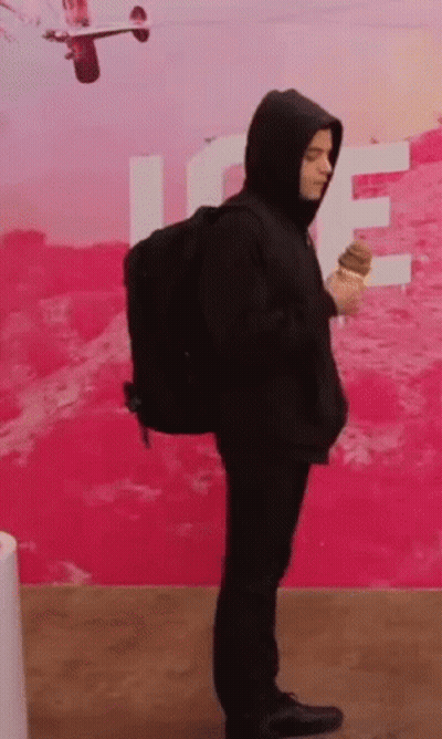 A Man In A Hooded Jacket Is Holding An Ice Cream Cone . GIF