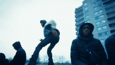 A Man In A Hooded Jacket Is Jumping In The Air GIF