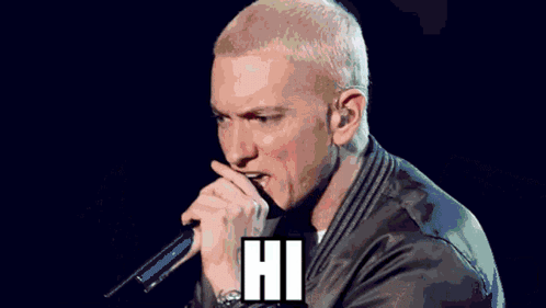 A Man In A Hooded Jacket Is Singing Into A Microphone With The Words " My Name Is " Below Him GIF