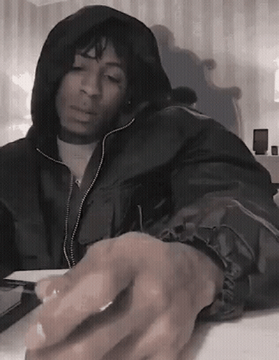 A Man In A Hooded Jacket Is Sitting At A Table With His Hands On The Keyboard . GIF