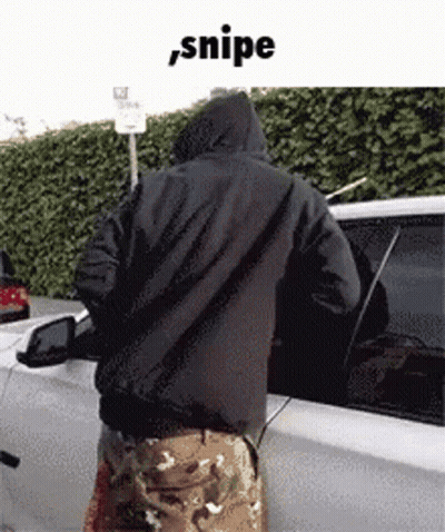 A Man In A Hooded Jacket Is Standing Next To A White Car . GIF
