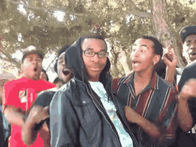 A Man In A Hooded Jacket Is Surrounded By A Group Of People . GIF