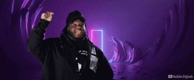 A Man In A Hooded Jacket Stands In Front Of A Sign That Says Mi Escena Musical GIF