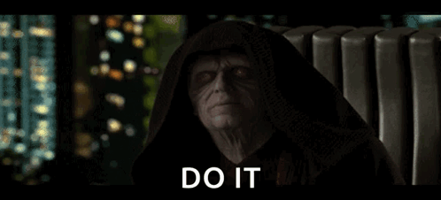 A Man In A Hooded Robe Is Sitting In A Chair With The Words `` Do It '' Written On The Screen . GIF