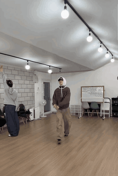 A Man In A Hooded Sweatshirt Is Dancing In A Room GIF