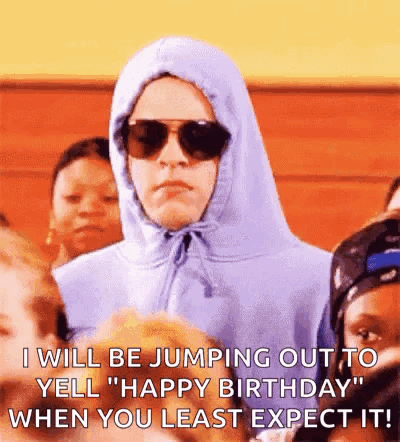 A Man In A Hoodie And Sunglasses Is Jumping Out To Yell `` Happy Birthday '' When You Least Expect It . GIF