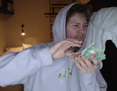 A Man In A Hoodie Is Holding A Piece Of Fruit In His Hands GIF