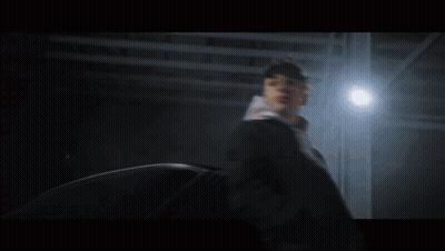 A Man In A Hoodie Is Standing Next To A Car At Night GIF