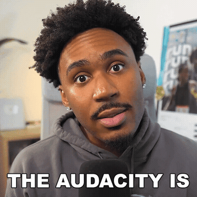 A Man In A Hoodie Is Talking Into A Microphone With The Words " The Audacity Is " Behind Him GIF