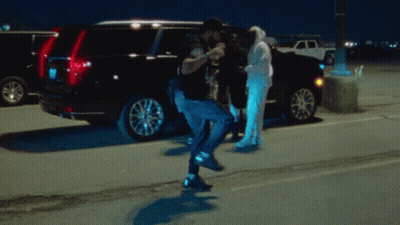 A Man In A Hoodie Stands In Front Of A Black Suv GIF