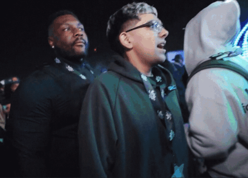 A Man In A Hoodie With The Word Icon On It Stands In A Crowd GIF