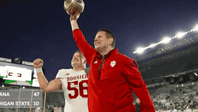 A Man In A Hoosier 56 Jersey Holds Up A Football GIF