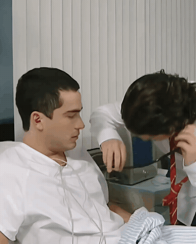 A Man In A Hospital Gown Is Talking To Another Man In A Red Tie GIF