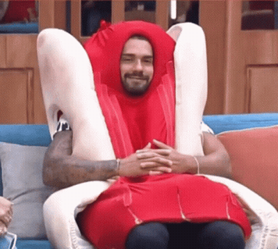 A Man In A Hot Dog Costume Is Sitting On A Couch With His Legs Crossed . GIF