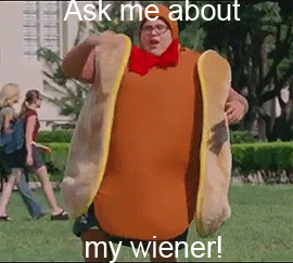 A Man In A Hot Dog Costume Is Standing In The Grass . GIF