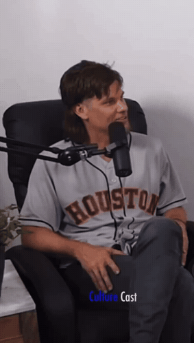 A Man In A Houston Jersey Sits In A Chair In Front Of A Microphone GIF