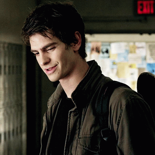 A Man In A Jacket Is Smiling In Front Of An Exit Sign GIF