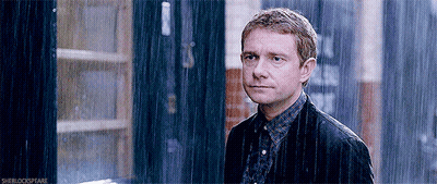 A Man In A Jacket Is Standing In The Rain Looking At The Camera . GIF