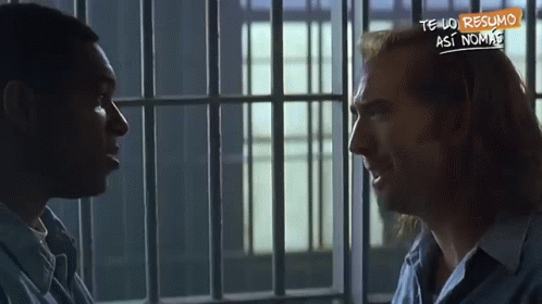 A Man In A Jail Cell Talking To Another Man With A Sign That Says Tengo Resumo GIF