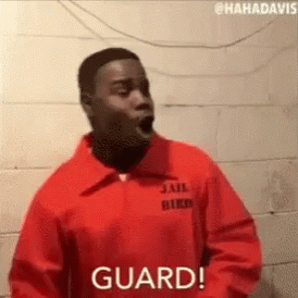 A Man In A Jail Uniform Is Standing In Front Of A Brick Wall With His Mouth Open . GIF