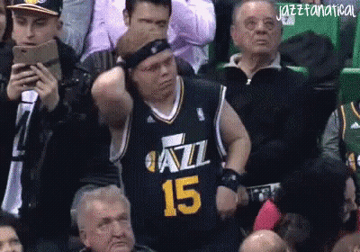 A Man In A Jazz Jersey Is Sitting In The Stands Watching A Game GIF