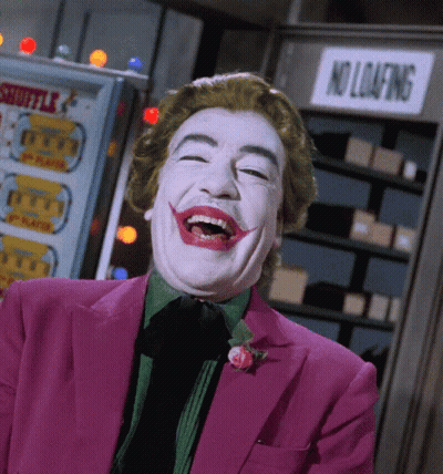 A Man In A Joker Costume Is Laughing In Front Of A No Loafing Sign GIF