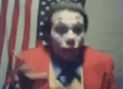 A Man In A Joker Costume Is Standing In Front Of An American Flag . GIF