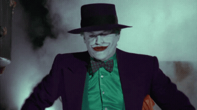 A Man In A Joker Costume Is Wearing A Green Shirt And A Purple Hat GIF