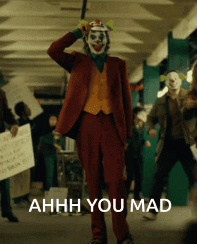 A Man In A Joker Costume Stands In Front Of A Sign That Says Ahhhh You Mad GIF