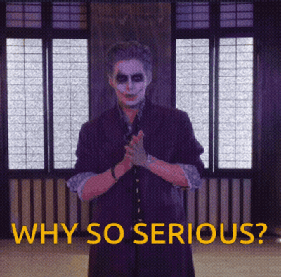 A Man In A Joker Costume Stands In Front Of A Window With The Words Why So Serious Below Him GIF