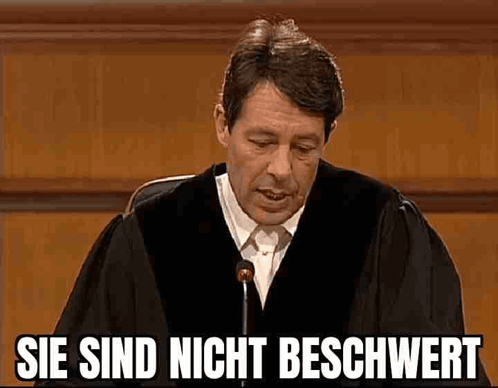 A Man In A Judge 'S Robe Is Giving A Speech In Front Of A Microphone In A Courtroom . GIF