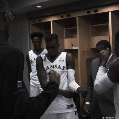 A Man In A Kansas Jersey Is Being Helped By Another Man GIF