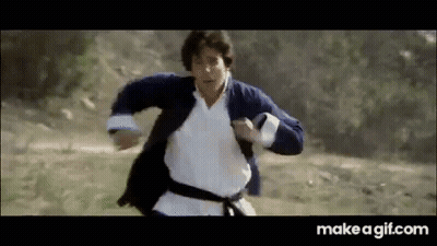 A Man In A Karate Outfit Is Running Through A Field . GIF