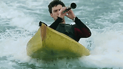 A Man In A Kayak Playing A Trumpet In The Water GIF