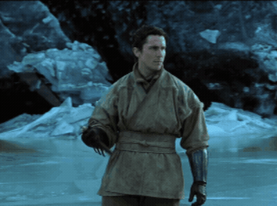 A Man In A Kimono And Gloves Stands In Front Of A Frozen Body Of Water GIF