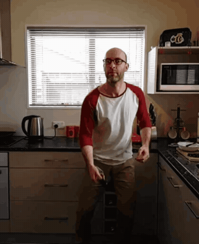 A Man In A Kitchen Wearing Glasses And A Red And White Shirt With The Letter O On It GIF