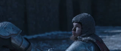 A Man In A Knight 'S Armor Is Holding A Sword In Front Of A Crowd With A Banner That Says Mm GIF