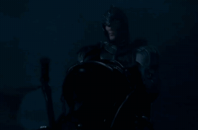 A Man In A Knight 'S Armor Is Holding A Sword In The Dark . GIF