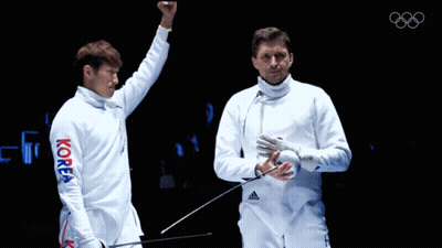 A Man In A Korea Shirt Holds His Fist Up In The Air GIF