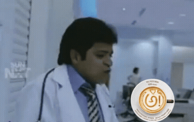 A Man In A Lab Coat Is Sitting In Front Of A Cup Of Coffee That Says Nespresso GIF
