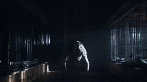 A Man In A Lab Coat Is Standing In The Dark GIF