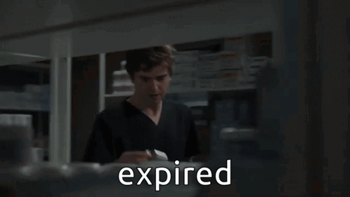 A Man In A Lab Coat Is Talking To Another Man In A Pharmacy And The Word Expired Is Visible GIF